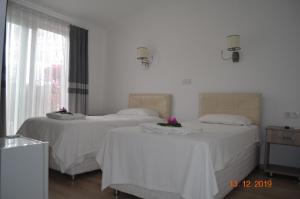 two beds in a room with white walls at Hotel Uygar in Fethiye