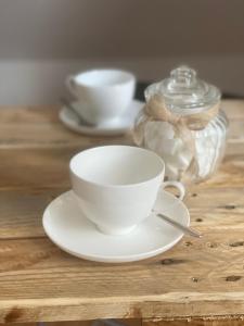 una taza blanca y un platillo sobre una mesa de madera en Steigerwaldblick Apartments Burgebrach en Burgebrach