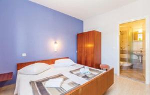 ADRIATIC apartmani A2-A6, RAB في راب: غرفة نوم بسرير وجدار ازرق