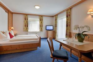 een hotelkamer met een bed, een bureau en een tafel bij Pension Eberharter in Mayrhofen