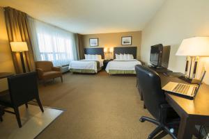 a hotel room with two beds and a desk with a computer at Quality Inn & Suites PE Trudeau Airport in Dorval