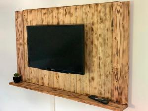 a flat screen tv on a wall with a wooden shelf at Steigerwaldblick Apartments Burgebrach in Burgebrach