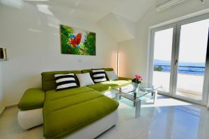 a living room with a green couch and a large window at Apartments Petrovac in Zavala