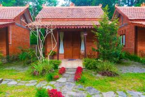 een stenen huis met een deur en bloemen in de tuin bij Villa Mak Cik in Yogyakarta