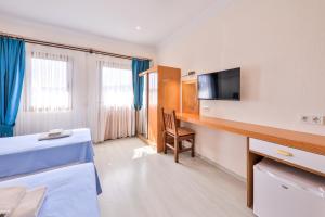 a room with a bed and a desk with a television at St. Nicholas Pension in Patara
