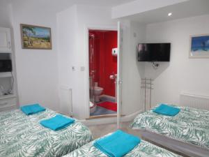 two beds in a room with a mirror and a bathroom at The Salendine in Blackpool