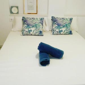 Una cama con una toalla enrollada azul. en Apartamento Ducal 1ª linea by Hugo Beach, en Gandía