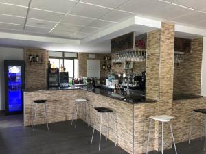 a bar with bar stools in a room with brick walls at Pensión Tasaga in O Pino 