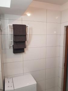 a white tiled bathroom with a toilet and towels at Studio Ines in Mamaia Nord