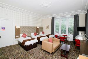 una habitación de hotel con 2 camas y una silla en Albion Hotel, en Glasgow