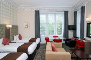 Cette chambre d'hôtel comprend deux lits, une table et des chaises. dans l'établissement Albion Hotel, à Glasgow