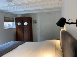 1 dormitorio con 1 cama con lámpara y puerta en t Melkhuisje - EV lader aanwezig! en Haaksbergen