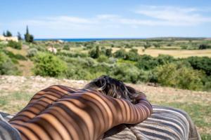 a person laying on a blanket looking out over a field at I Carusi Relais in Noto