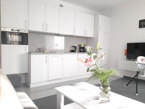 a white kitchen with a table and a vase with flowers at Apartamenty Słoneczna Przystań in Łeba