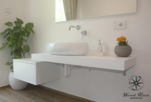 ein weißes Badezimmer mit einem Waschbecken und einem Spiegel in der Unterkunft Wind Rose Apartments 2 in Nago-Torbole
