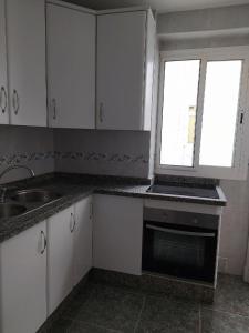 a kitchen with white cabinets and a sink and a window at COSTA DE ALMERIA PLAYA in Almería