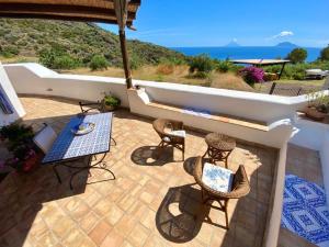un patio con tavolo, sedie e vista sull'oceano di Case Vacanze Marina Longo a Santa Marina Salina