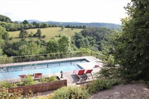 - une piscine avec 2 chaises rouges sur une terrasse dans l'établissement Les Terrasses de Labade Chambres d'hôtes, à Coubisou