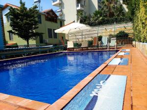a large blue swimming pool with benches and an umbrella at Villa Angela in Vlorë