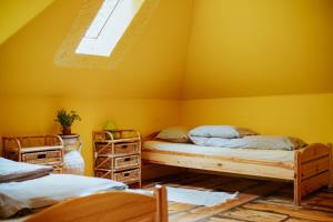 two beds in a room with yellow walls at Kempings Ievlejas in Saka