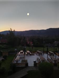 eine Gruppe Picknicktische mit dem Mond am Himmel in der Unterkunft Penzion u Marešů in Hřensko