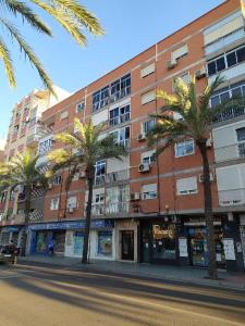 a building with palm trees in front of a street at COSTA DE ALMERIA PLAYA in Almería
