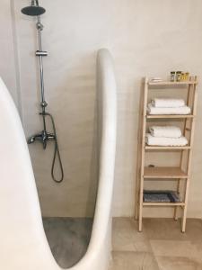 a bathroom with a bath tub and a shelf with towels at Nautilos in Tinos Town