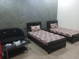 two beds and a couch in a room at Hotel Decent Lodge in Multan