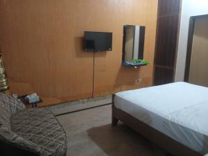 a bedroom with a bed and a tv on a wall at Hotel Decent Lodge in Multan