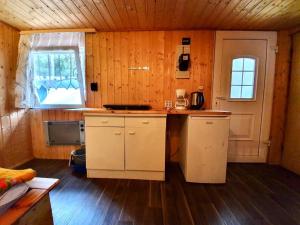 una cocina con armarios blancos, una ventana y una mesa en Feriensiedlung Schwalbennest, en Dranske