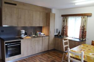 cocina con armarios de madera, fregadero y mesa en Haus Weideli en Saas-Grund
