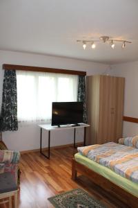 a room with two beds and a desk with a television at Haus Weideli, Dammstrasse 7 in Saas-Grund
