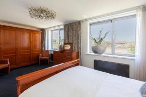 a bedroom with a bed and a desk and a window at Hotel La Rosa Amsterdam Beach in Zandvoort