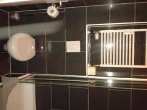 baño con espejo y pared de azulejos negros en Pension Levi, en Berlín