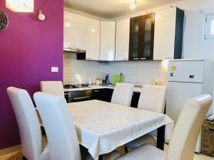 a kitchen with a white table and white chairs at Apartman Lala in Baška Voda