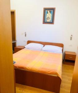 a bedroom with a bed with a orange and yellow blanket at Apartman Lala in Baška Voda