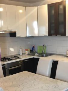 a kitchen with white cabinets and a sink and a table at Apartman Lala in Baška Voda +4 photos