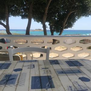 uma mesa e cadeiras numa praia com o oceano em Villa Fascinosa em Portopalo