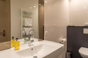La salle de bains blanche est pourvue d'un lavabo et de toilettes. dans l'établissement Hotel La Rosa Amsterdam Beach, à Zandvoort