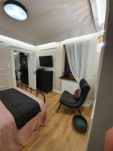 a bedroom with a bed and a chair and a television at Apartament w sercu Zamojskiej Starówki in Zamość +5 photos