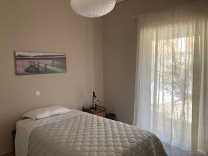 ein Schlafzimmer mit einem weißen Bett und einem Fenster in der Unterkunft Elegant house by the sea with pool in Akráta + 15 Fotos