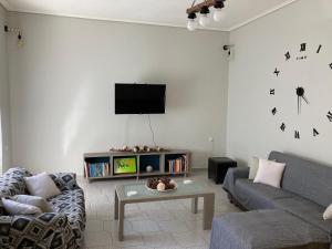 ein Wohnzimmer mit einem Sofa und einem Fernseher an der Wand in der Unterkunft Elegant house by the sea with pool in Akráta