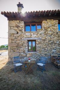Los Narros的住宿－Casa rural La Tenada，石头建筑前的两把椅子和一张桌子