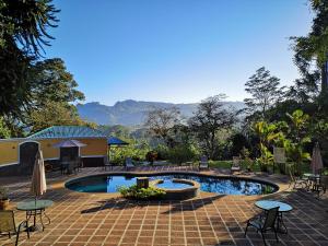 a swimming pool with tables and chairs and a building at Hotel Villa Florencia in Turrialba