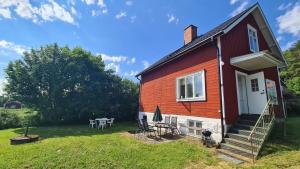 a dog is standing outside of a red house at Symaskinshuset Järvsö in Järvsö