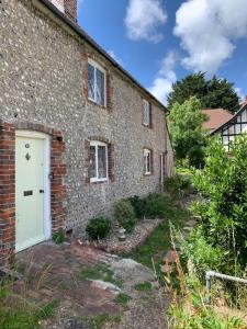 an old brick house with a white door in a yard at Cosy Flint Cottage in Eastbourne
