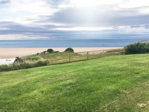 a field with a fence next to a beach at Ocean Edge Holiday Home in Heysham