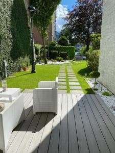 una terrazza in legno con 2 sedie bianche e un prato di Villa Bianca a Como