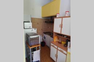 una pequeña cocina con armarios blancos y nevera. en Appartement Barèges, en Barèges