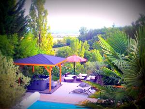 a patio with an umbrella and chairs and a pool at L'Hermine Occitane B&B in Gratens